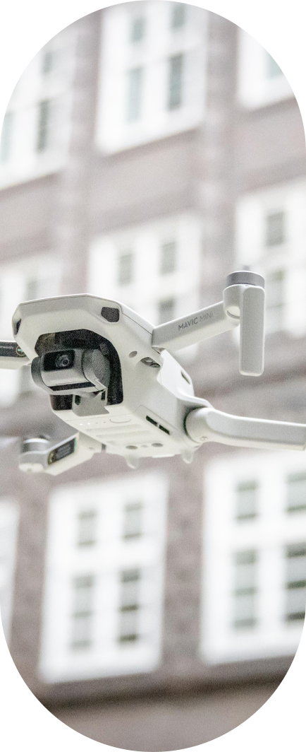 Fliegende weiße Drohne vor Hauswand