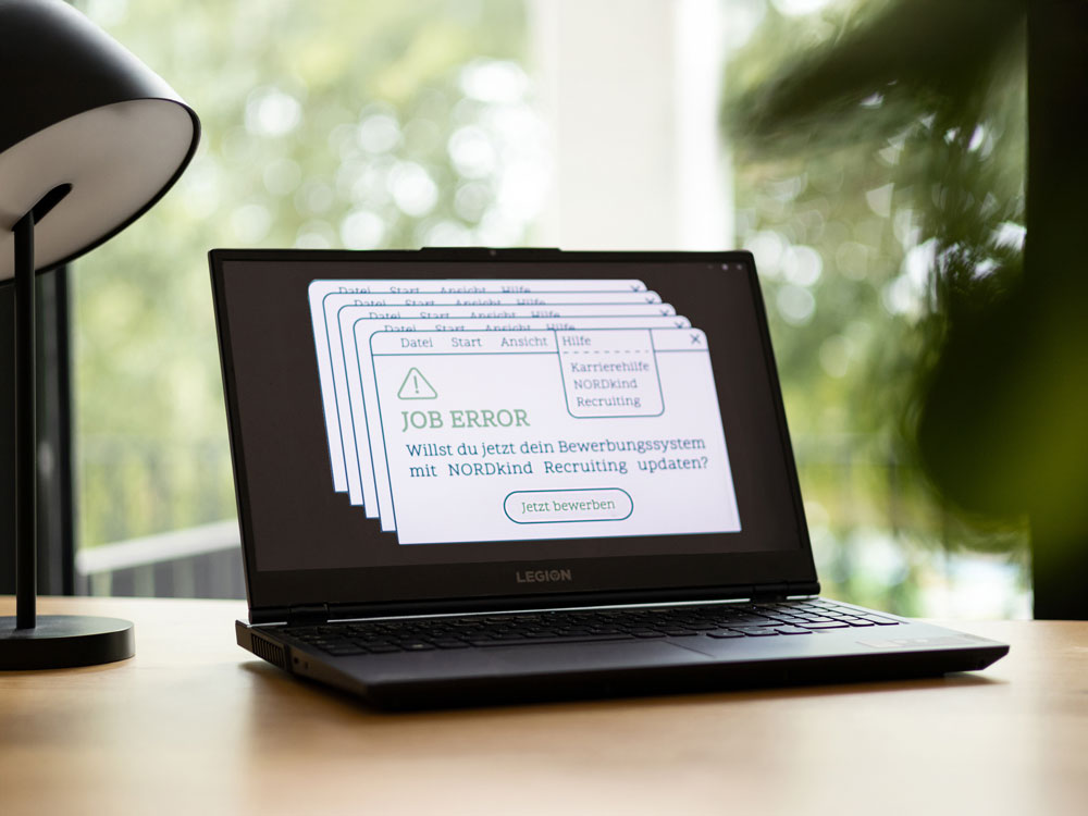 Laptop auf Schreibtisch, links daneben eine kleine Lampe.